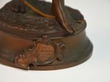 a bronze statue of a woman holding a tennis racquet