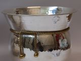 a silver bowl with a chain around it on a table
