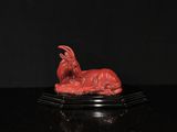 statue d'une chèvre rouge sur un socle noir