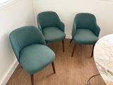 trois chaises vertes dans un coin de la pièce, près d'une table