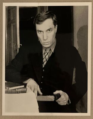 photographie en noir et blanc d'un homme en costume-cravate tenant un livre