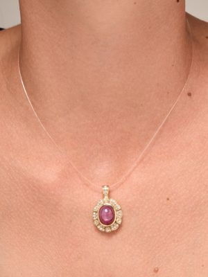 the woman is wearing a necklace that has a pink stone on it
