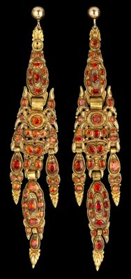deux paires de boucles d'oreilles en verre doré et rouge sur fond noir