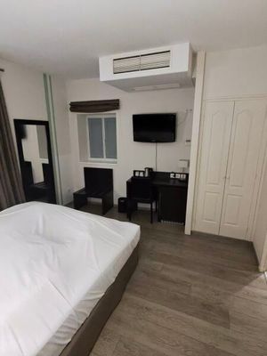 a bed with a white comforter and a flat screen tv on the wall