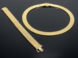 un ensemble composé d'un collier et d'un bracelet en or, posé sur un fond noir