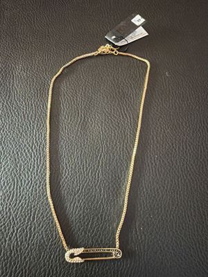 un collier en or orné d'une barre, posé sur une surface noire