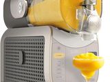 un extracteur de jus avec un verre de jus d'orange à côté