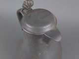an antique silver teapot with a lid on a grey background