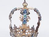 une couronne richement décorée, surmontée d'une croix, posée sur un fond blanc