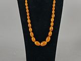 an orange beaded necklace and bracelet set on a mannequin