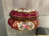 une vitrine en verre sur laquelle est posée une boîte rose et dorée