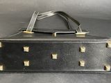 black leather purse with rivets and gold accents on it