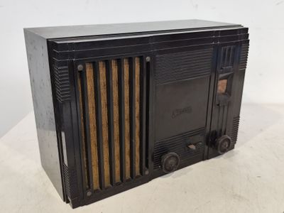 une vieille radio noire posée sur une table près d'un mur blanc