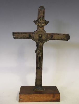 un crucifix ancien en bronze posé sur un socle en bois