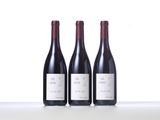 three bottles of red wine are lined up on a table