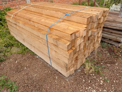 un tas de bois posé par terre devant un bâtiment en briques