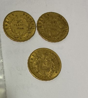 three gold coins sitting next to each other on a white surface