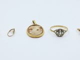 a group of five rings and a pendant on a white surface