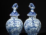 pair of blue and white vases with figures on top of them