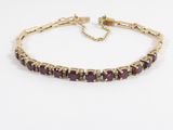 un bracelet en or orné de pierres violettes sur fond blanc