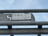 a ticket sitting on a metal fence with a blue sky in the background