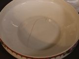 a white bowl with a gold handle and a white bowl with a gold handle on a black table