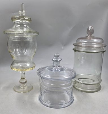 trois bocaux en verre avec leurs couvercles, posés sur une surface blanche