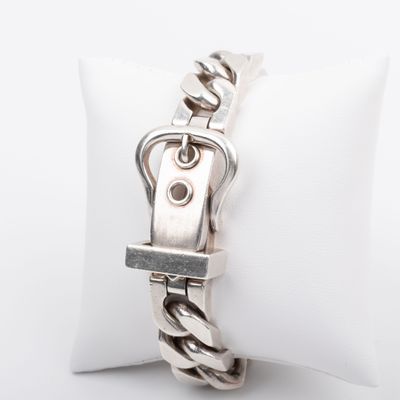 a close up of a bracelet on a pillow on a white surface