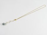 a necklace with a pearl and a gold chain on a white surface