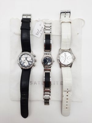 trois montres sont posées sur un tissu blanc, avec une étiquette de prix