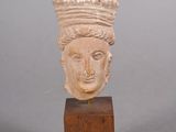 tête sculptée représentant une femme coiffée d'une couronne, posée sur un socle en bois