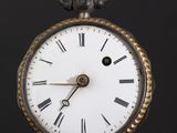 a close up of a pocket watch on a black surface