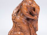 une sculpture en bois représentant une femme assise sur un rocher