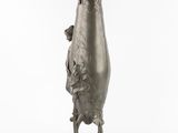 a silver vase that is on a stand on a white surface