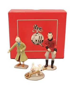 deux figurines représentant un homme et un chien devant une boîte rouge