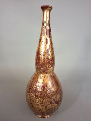 a gold and red vase sitting on a table
