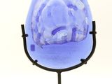 purple glass sculpture of a heart on a stand on a white background