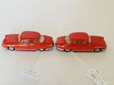 two red toy cars sitting next to each other on a table