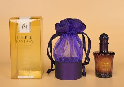 des flacons de parfum et un sac violet posés l'un à côté de l'autre sur une table
