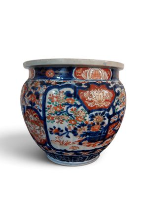 un vase bleu et orange muni d'un couvercle, posé sur une surface blanche