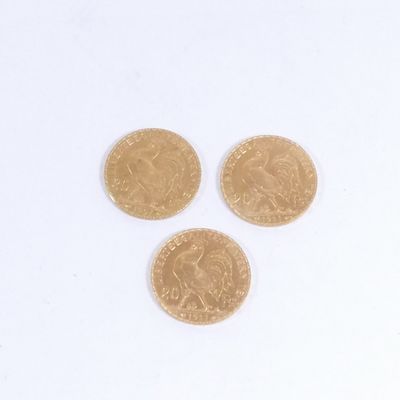trois pièces d'or posées l'une à côté de l'autre sur une surface blanche
