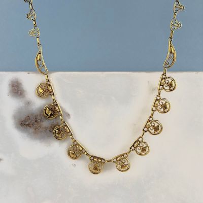 un gros plan d'un collier en or posé sur une surface en marbre