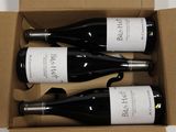 three bottles of wine in a cardboard box on a table