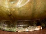 a close up of a bronze bowl on a wooden table