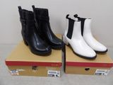 Deux paires de bottes noires et blanches sont posées sur une boîte.