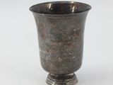 a silver cup that is sitting on a white surface