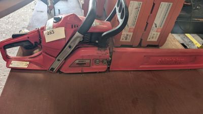 une tronçonneuse rouge posée sur une table en bois