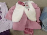 a pile of clothing that includes a pink coat, pink pants, and a white vest