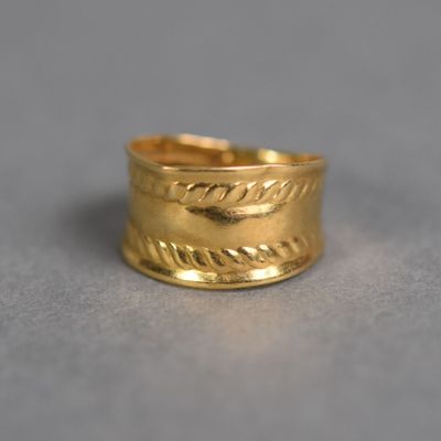 gros plan d'une bague en or sur une surface grise