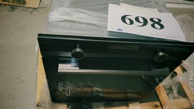 un four noir posé sur une palette dans un entrepôt